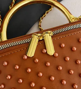 Close-up of golden zipper and rivet details on the brown textured chain handbag