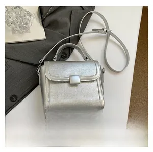 Detail of silver textured square handbag with metallic buckle and slim shoulder strap