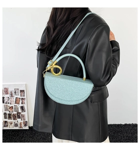 Detailed side view of mint green glitter saddle bag with golden metallic handle and strap