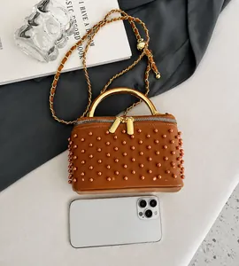 Brown leather crossbody bag size comparison with smartphone and chain strap detail