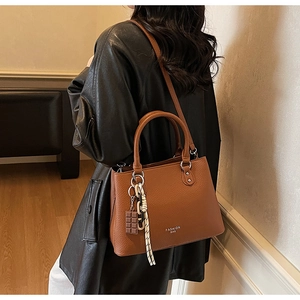 Detail of caramel litchi grain handbag with Fashion Bag gold foil and chocolate charm