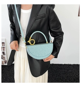 Detail of mint green semi-circular saddle bag with sequins and golden ring handle