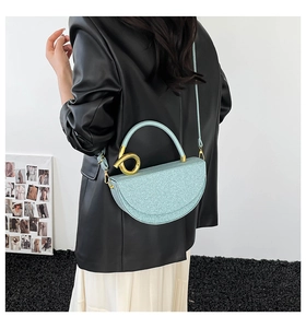 Detail view of light blue crescent bag with golden twist metal hardware and glitter finish