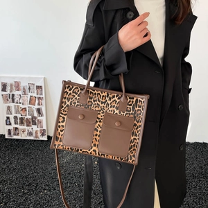 Fashionable leopard print tote bag with brown pockets shown on a model in a minimal setting