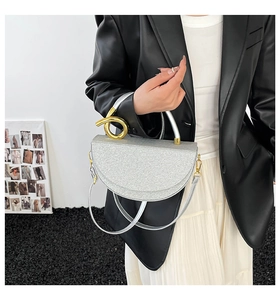 Detail of silver glitter saddle bag with a twisted gold handle and thin shoulder strap