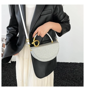 Detail of silver sequin saddle bag with creative gold spiral handle on female model