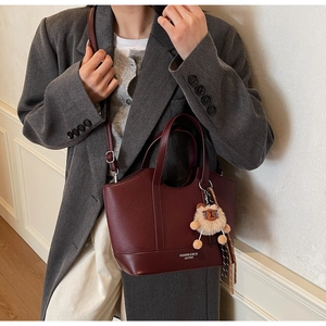 Detailansicht der weinroten Litschi-Tasche mit Schultergurt und Plüschtier-Anhänger