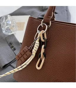 Detail of creative chocolate pendant with resin chain on litchi texture handbag