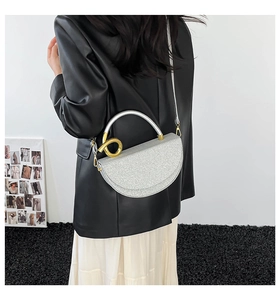 Macro detail of silver textured saddle bag with gold double-ring hardware and flap
