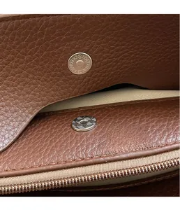 Detail of premium magnetic snap closure and texture on brown lychee grain leather bag