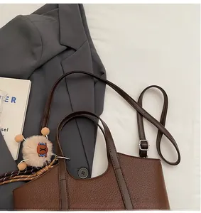 Detail der Eimer-Tasche aus Leder mit Lychee-Muster, verstellbarem Riemen und Plüsch-Anhänger