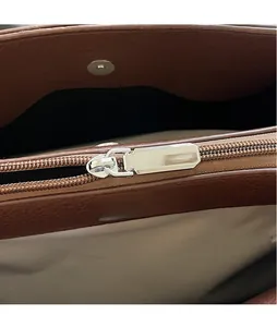 Detail of silver zipper slider and magnetic clasp on brown leather tote bag interior