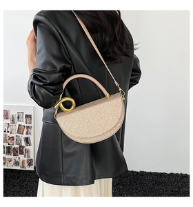 Detail view of champagne gold glitter crossbody bag with gold circular handle