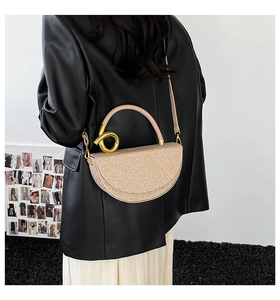 Detail of glitter champagne gold semi-circle handbag with a round metal handle and strap
