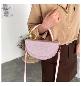 Detail of pink sequin saddle bag with creative gold twisted metal handle and slim strap