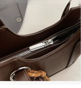 Detail eines silbernen Reißverschlusses und Webseils an einer braunen Beuteltasche