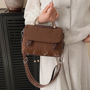 Vintage brown leather handbag with gold handle and woven crossbody strap displayed by model