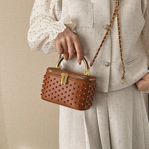 Brown vintage box bag with pearls and golden handle shown on tweed outfit