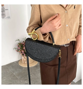 Detail of black semi-circle saddle bag featuring shimmering sequins and golden knotted handle