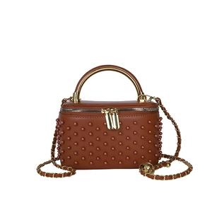 Brown leather box bag with stud embellishments and gold chain strap in a frontal view