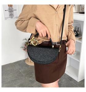Detailed view of black glitter crescent bag with gold metal handle and shimmer texture