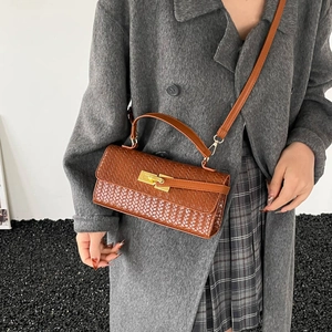 Borsa a tracolla marrone con trama intrecciata e chiusura dorata, indossata con cappotto