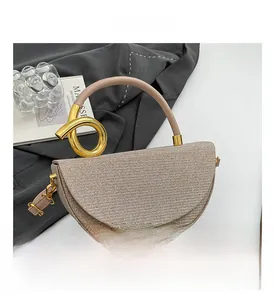 Detail of a beige woven saddle bag with a unique gold knot handle and adjustable strap