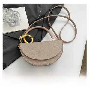 Close-up of champagne glitter semi-circular handbag with gold ring handle and leather strap