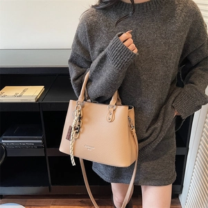 Chic beige lychee leather tote bag with FASHION BAG text and chain charm on a model