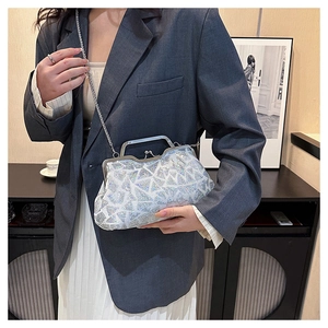 Detail of silver sequin shell bag with metal handle and chain strap on a grey blazer outfit