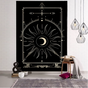 Black and gold tarot tapestry with sun and moon designs hanging on a white brick wall