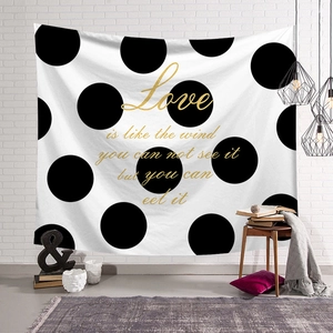 Detail of Nordic tapestry with gold quote and black dots on a white textured wall
