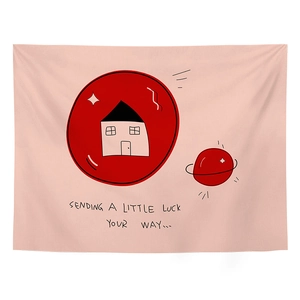 Detail of pink wall tapestry with red house graphics and Sending a Little Luck text