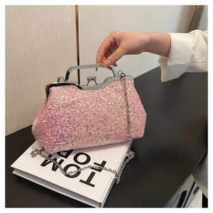 Detail of bright pink sequin evening bag with silver metal handle on white book props