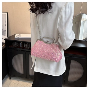 Pink sequin evening clutch bag with chain strap shown on shoulder with white blazer