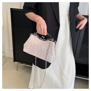 Close-up of a silver sequin evening bag featuring a metal handle and chain strap