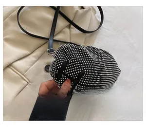 Detail view of sparkly silver rhinestones on a soft cloud clutch with black leather strap