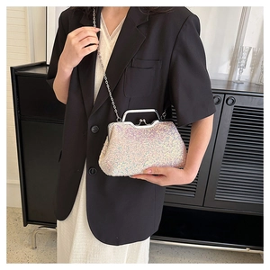 Detailed view of pink sequin clutch bag with silver chain strap worn by a model
