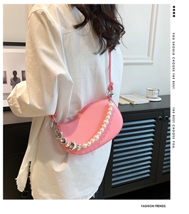 Detail of pink crescent bag with pearl chain strap and silver heart pendant charm