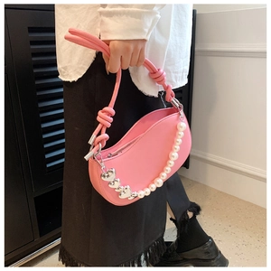 Detail of pink shoulder bag featuring pearl chain with heart charms and knotted handle