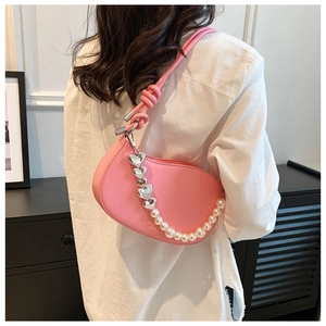 Pink crescent underarm bag with decorative pearl and heart chain detail on model