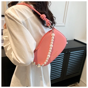 Detail of pink curved shoulder bag with large pearl chain and knotted shoulder strap