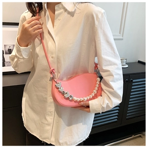 Detail of pink half-moon crossbody bag featuring heart charms and pearl chain strap