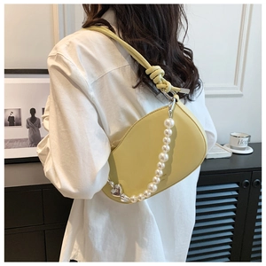 Detail of yellow crescent shoulder bag with pearl chain and heart charm detail