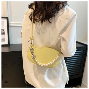 Detail of light yellow crescent bag with heart metal and white pearl decorative chain