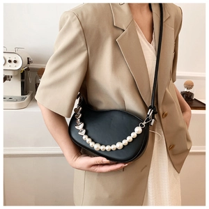 Detail of black saddle bag featuring pearl chain and silver heart buckle accents