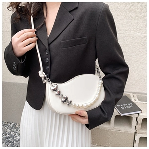 White crescent crossbody bag detail with heart charms and pearl chain accessory