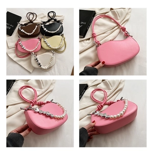 Detail of a half-moon shoulder bag featuring pearl chains and silver heart charms