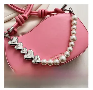 Detail of pink half-moon bag with silver metal hearts and pearl chain decoration