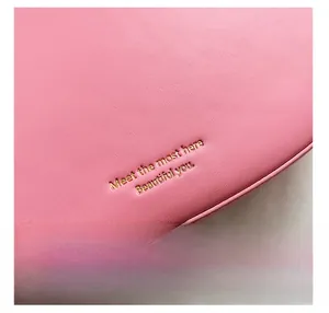 Macro detail of pink leather texture with elegant gold foil stamped quote on bag